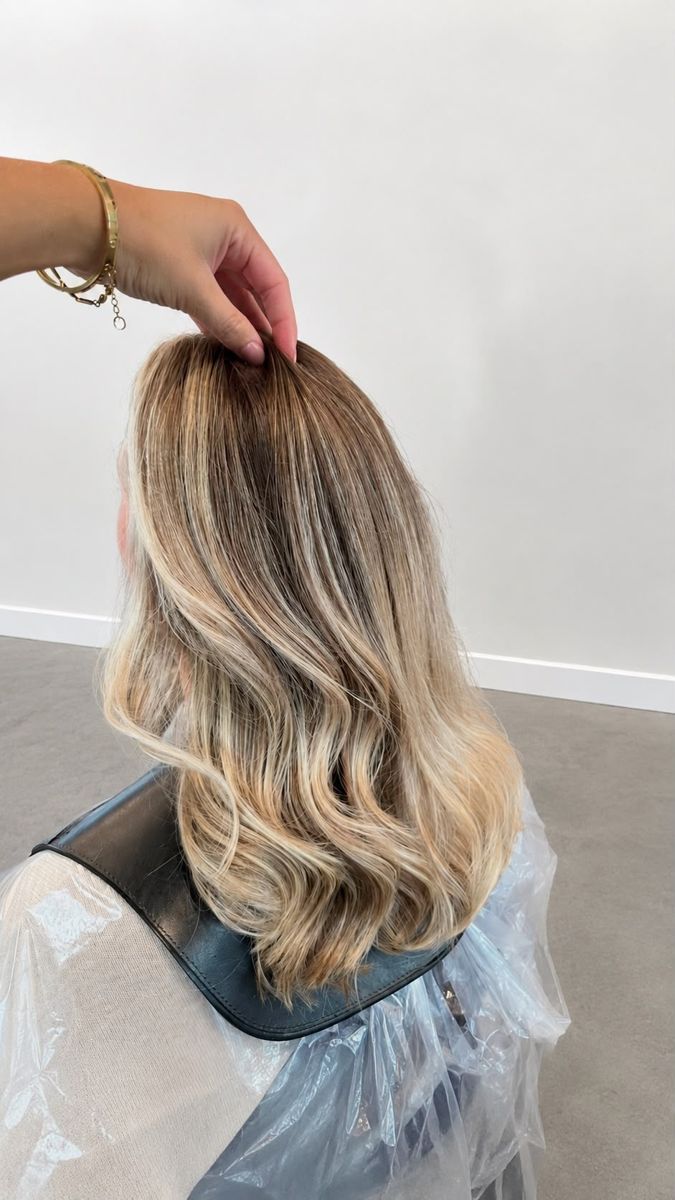 Halflang haar met blonde balayage en zachte golven, van achteren gezien